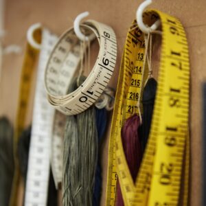 A row of hooks and tape measures on a tool board.