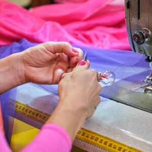 Unrecognizable dressmaker cutting the thread to threading sewing machine.