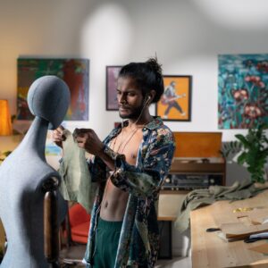 Young modern tailor trying paper pattern of new apparel on mannequin